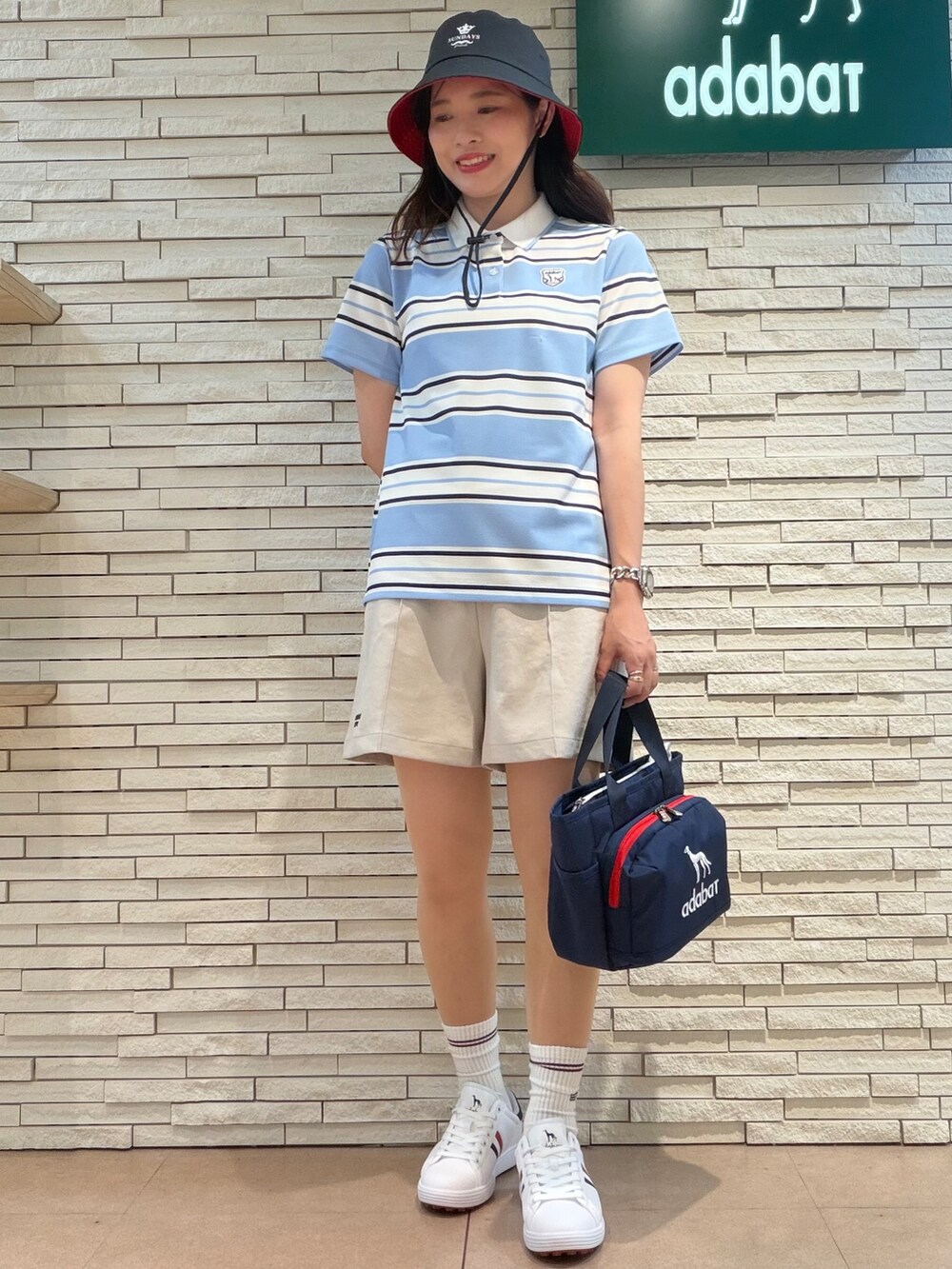 ブルー系のポロシャツ、ベージュ系のその他パンツ、ブルー系のトートバッグを着用したレディースの夏コーディネートの4枚目の写真