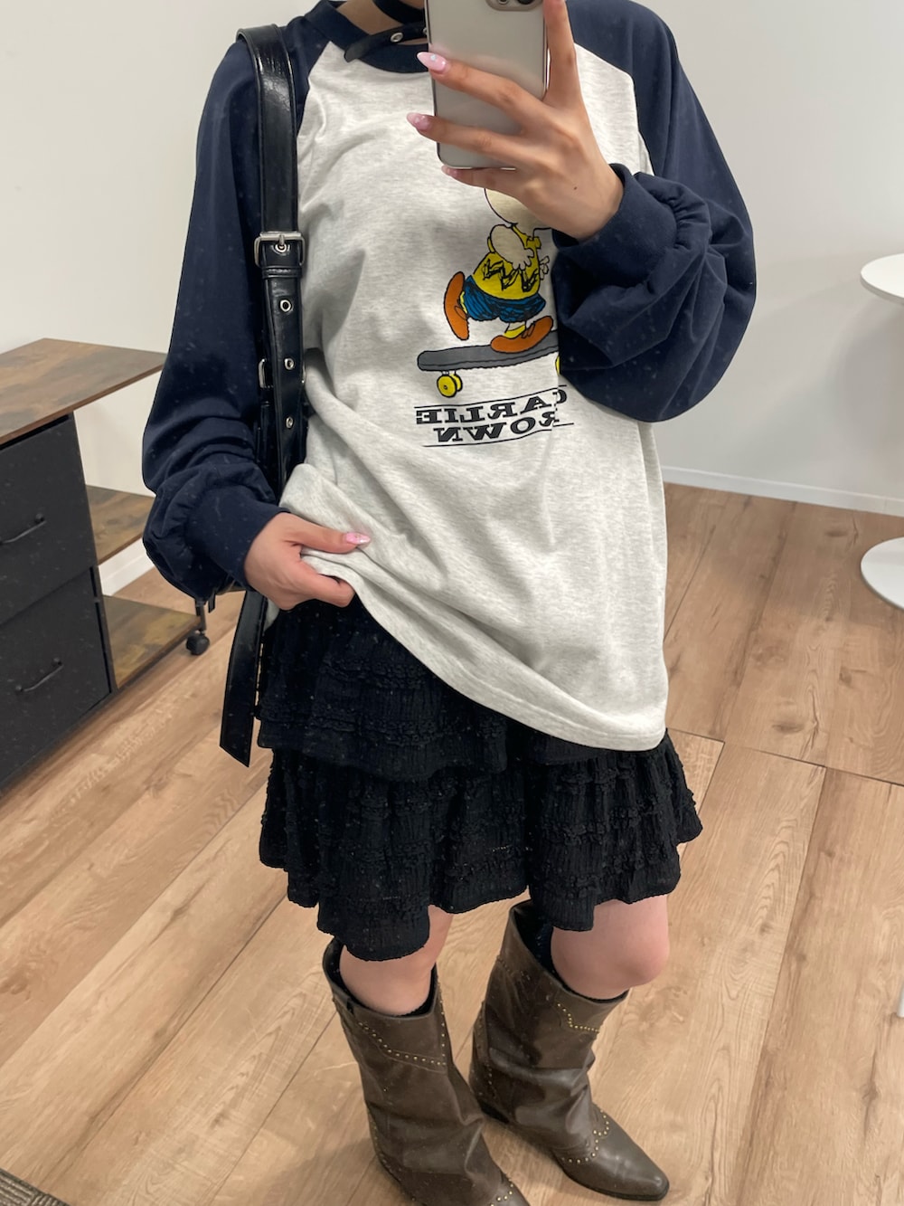 ブラウン系のブーツ、ブラック系のショルダーバッグ、ブラック系のスカートを着用したレディースの秋コーディネートの3枚目の写真