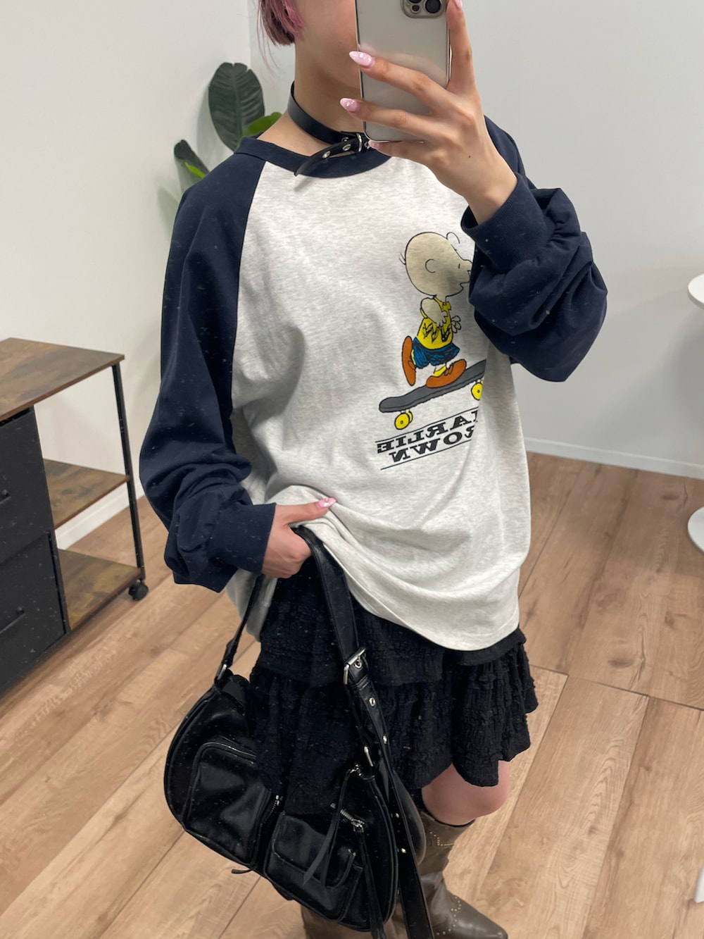 ブラウン系のブーツ、ブラック系のショルダーバッグ、ブラック系のスカートを着用したレディースの秋コーディネートの2枚目の写真