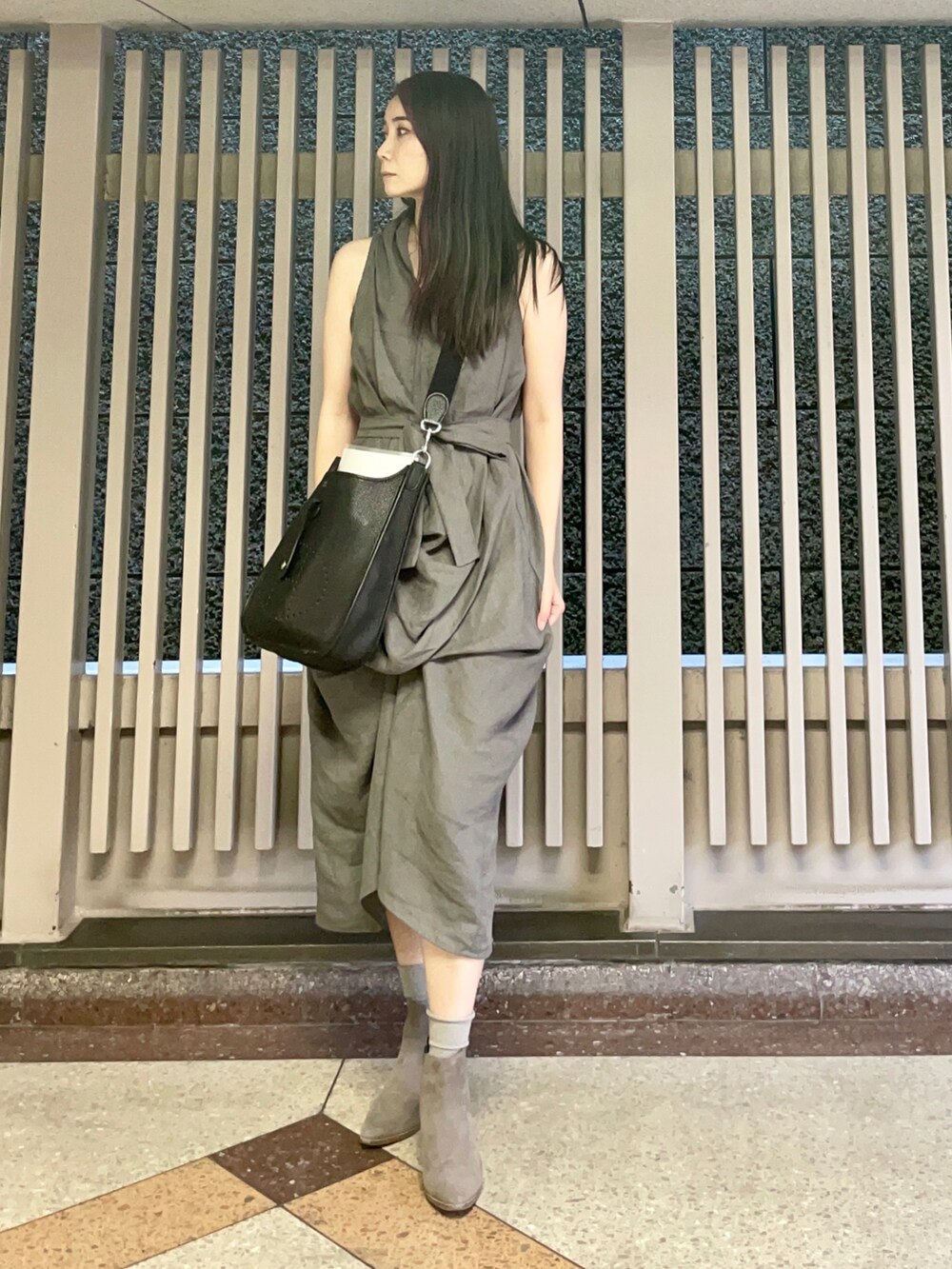 グレー系のワンピース、グレー系のブーツ、ブラック系のショルダーバッグを着用したレディースの秋コーディネートの2枚目の写真