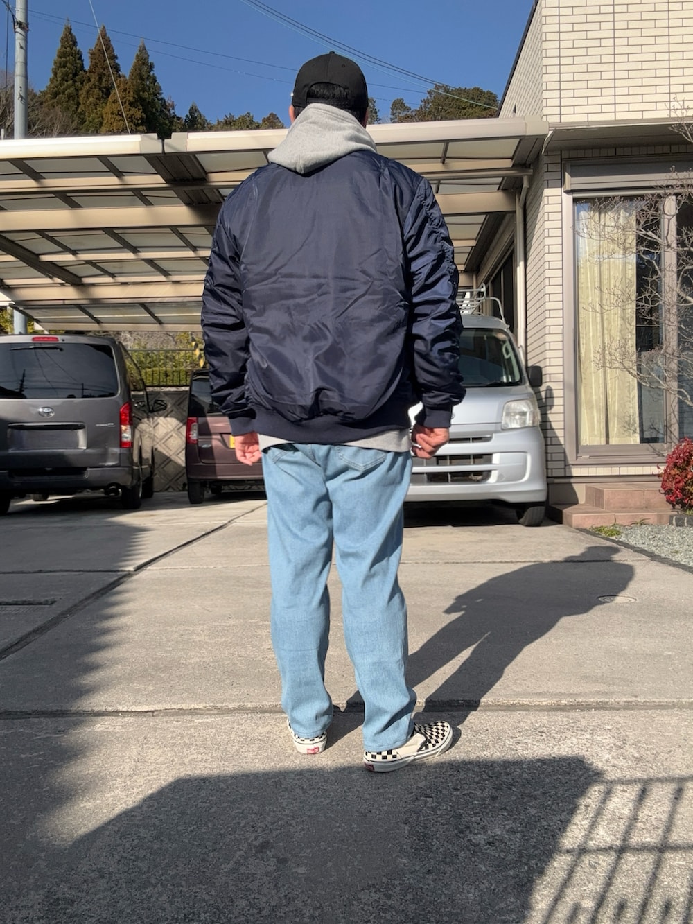 グレー系のパーカー、ブルー系のMA-1、ブルー系のデニムパンツを着用したメンズの春コーディネートの2枚目の写真