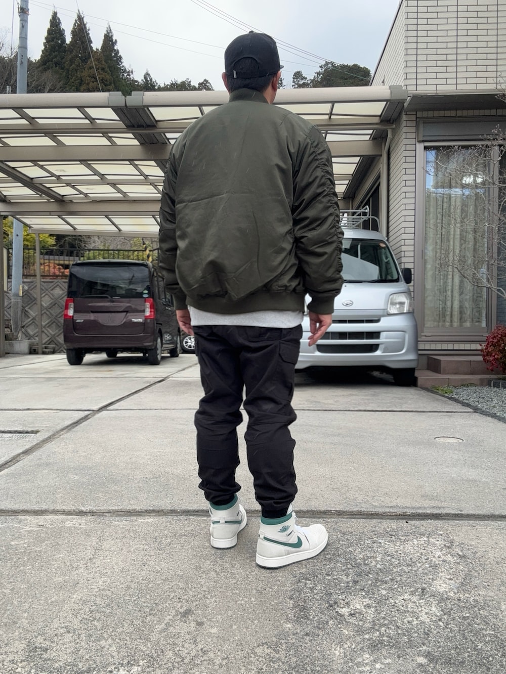 グレー系のスウェット、グリーン系のMA-1、ブラック系のカーゴパンツを着用したメンズの春コーディネートの2枚目の写真