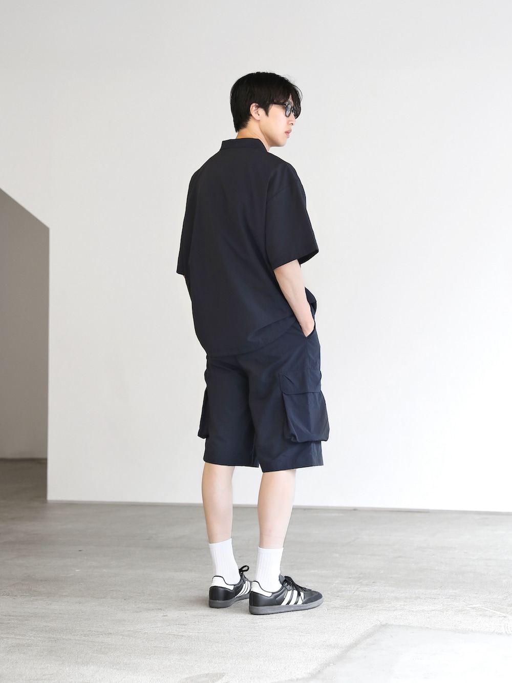 ブルー系のポロシャツ、ブルー系のカーゴパンツ、ブラック系のスニーカーを着用したメンズの夏コーディネートの3枚目の写真