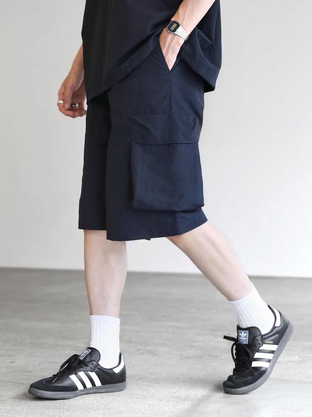 ブルー系のポロシャツ、ブルー系のカーゴパンツ、ブラック系のスニーカーを着用したメンズの夏コーディネートの5枚目の写真