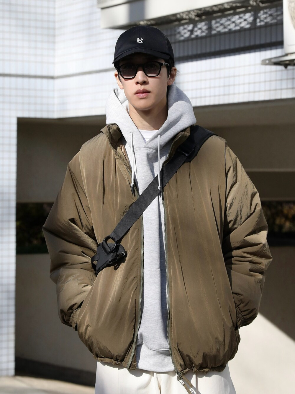 ベージュ系のジャケット/アウター、グレー系のパーカー、ホワイト系のチノパンツを着用したメンズの冬コーディネートの3枚目の写真