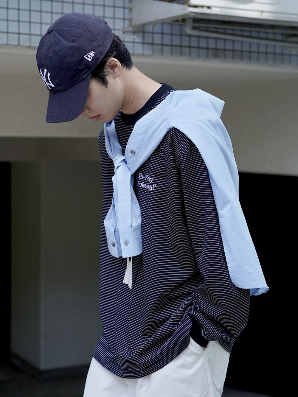 ホワイト系のチノパンツ、ホワイト系のトートバッグ、ブルー系のスニーカーを着用したメンズの春コーディネートの3枚目の写真