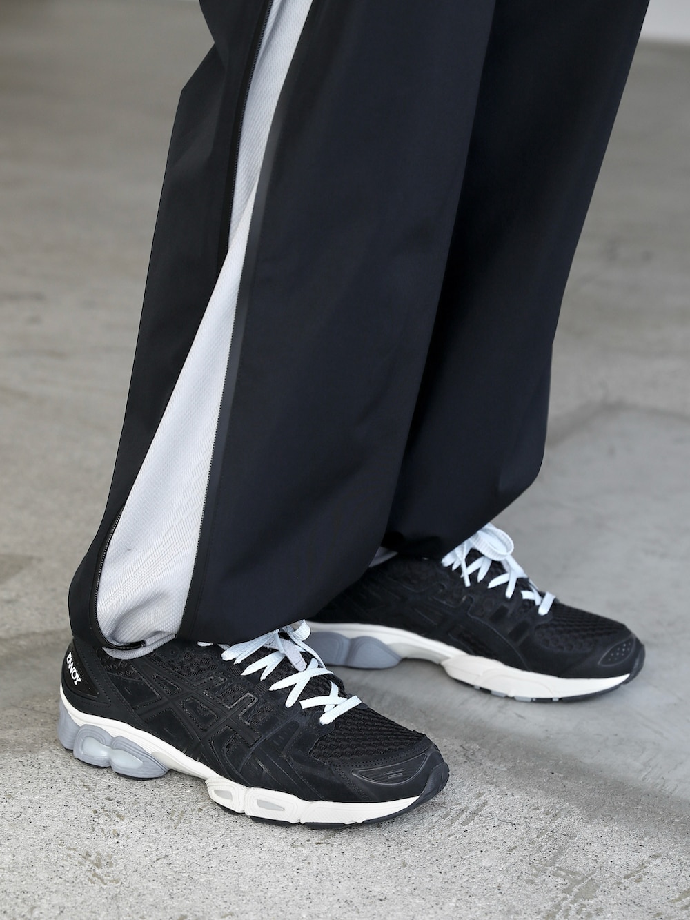 ブラック系のポロシャツ、ブラック系のパンツ、ブラック系のスニーカーを着用したメンズの春コーディネートの5枚目の写真