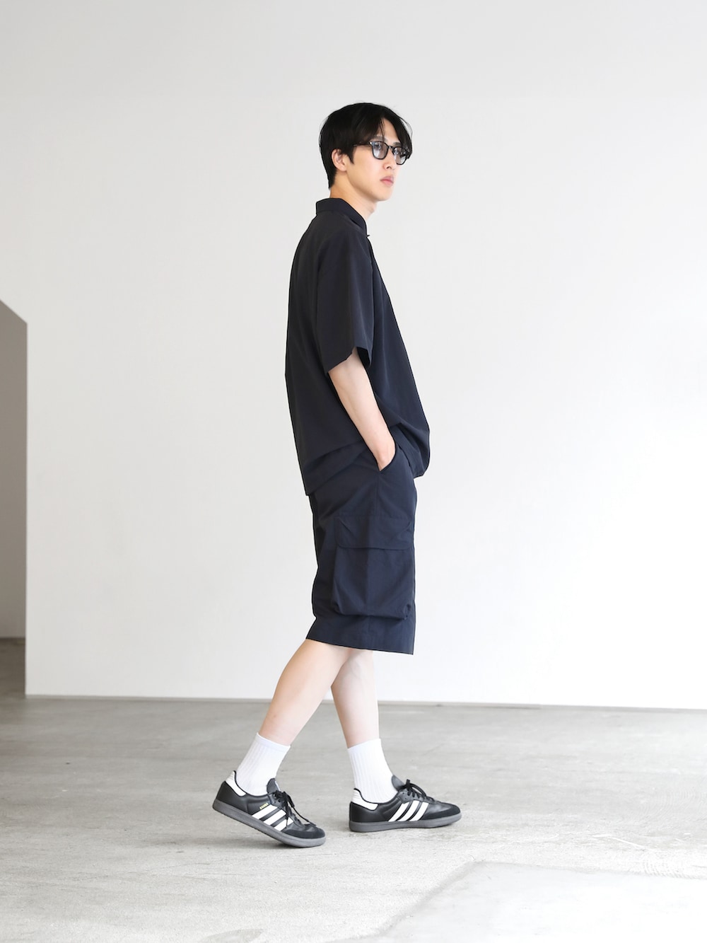 ブルー系のポロシャツ、ブルー系のカーゴパンツ、ブラック系のスニーカーを着用したメンズの夏コーディネートの2枚目の写真