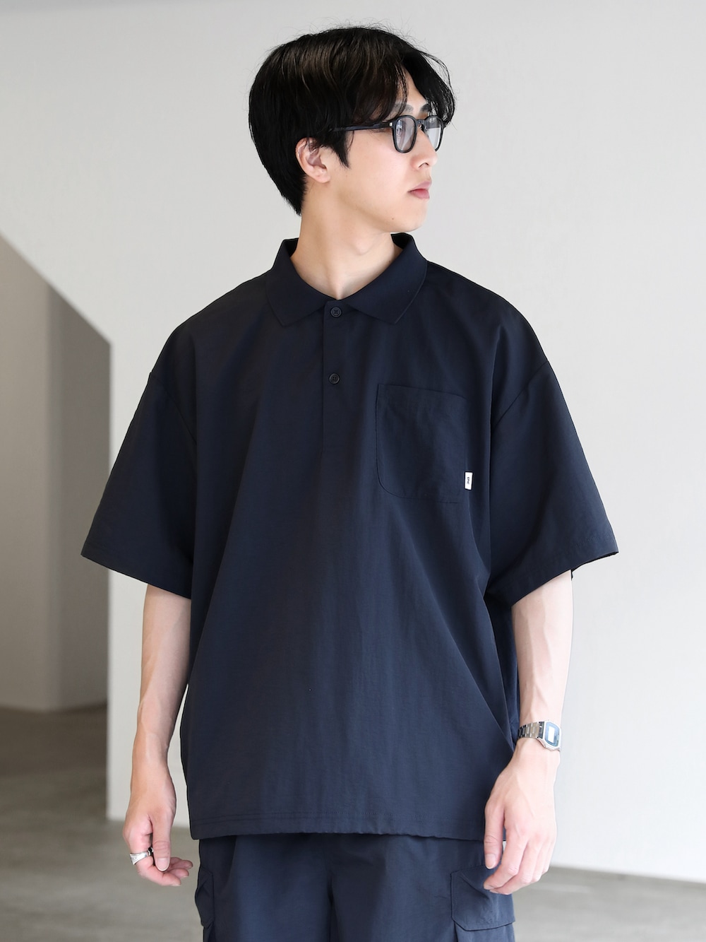 ブルー系のポロシャツ、ブルー系のカーゴパンツ、ブラック系のスニーカーを着用したメンズの夏コーディネートの4枚目の写真