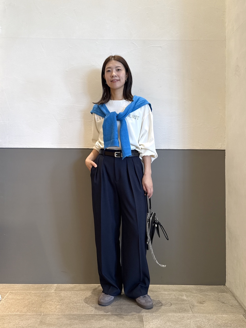 ブルー系のスラックス、ホワイト系のTシャツ/カットソー、ブラック系のベルトを着用したレディースの秋コーディネートの4枚目の写真