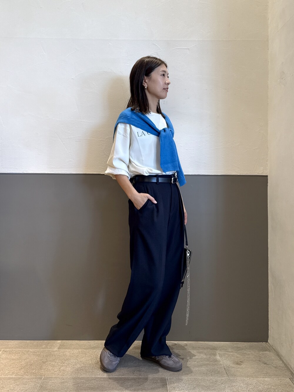 ブルー系のスラックス、ホワイト系のTシャツ/カットソー、ブラック系のベルトを着用したレディースの秋コーディネートの2枚目の写真