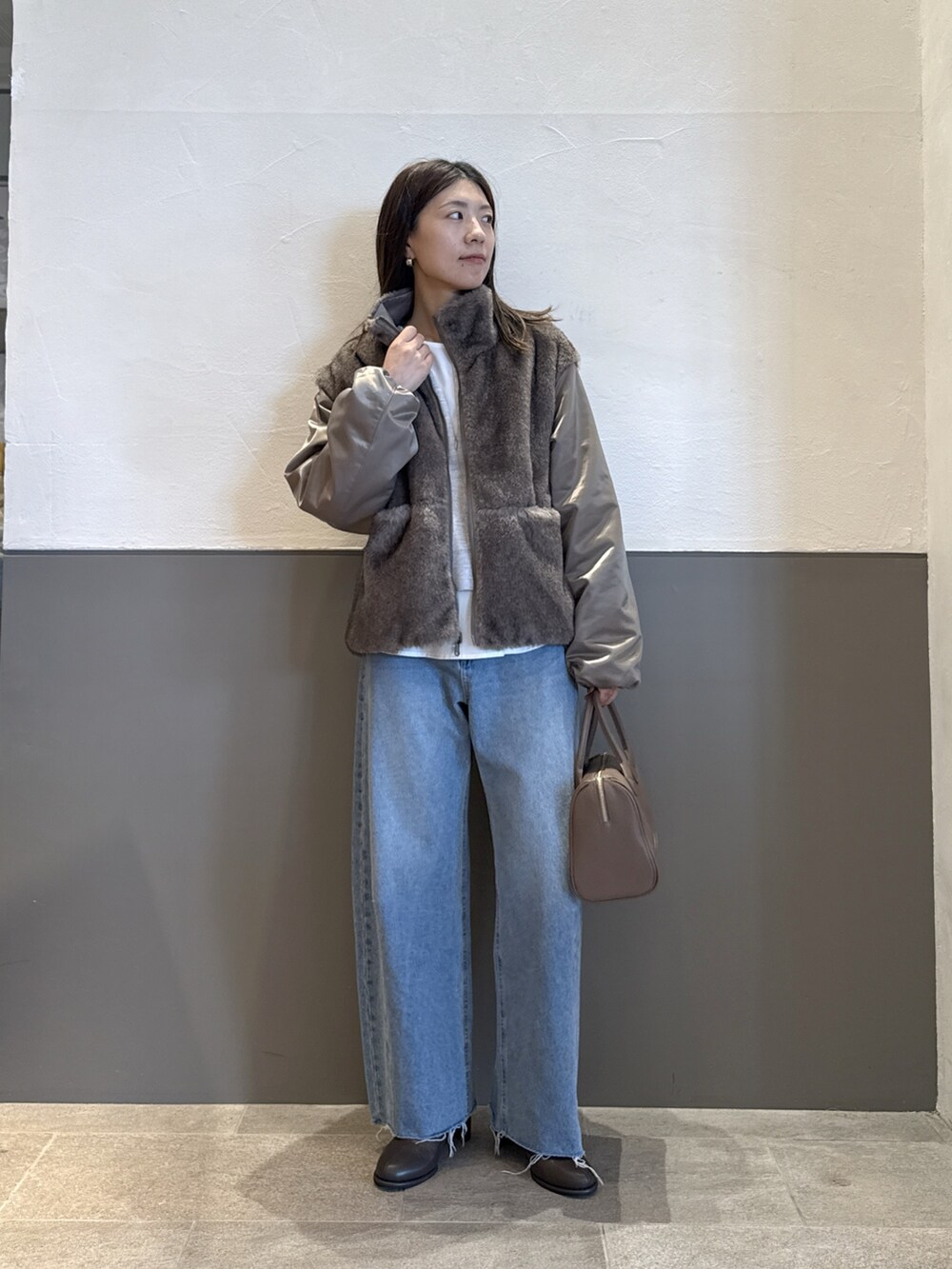 グリーン系のブルゾン、ブルー系のデニムパンツ、グレー系のニット/セーターを着用したレディースの秋コーディネートの2枚目の写真