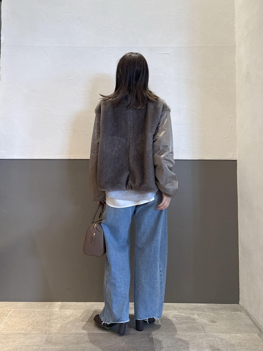 グリーン系のブルゾン、ブルー系のデニムパンツ、グレー系のニット/セーターを着用したレディースの秋コーディネートの3枚目の写真