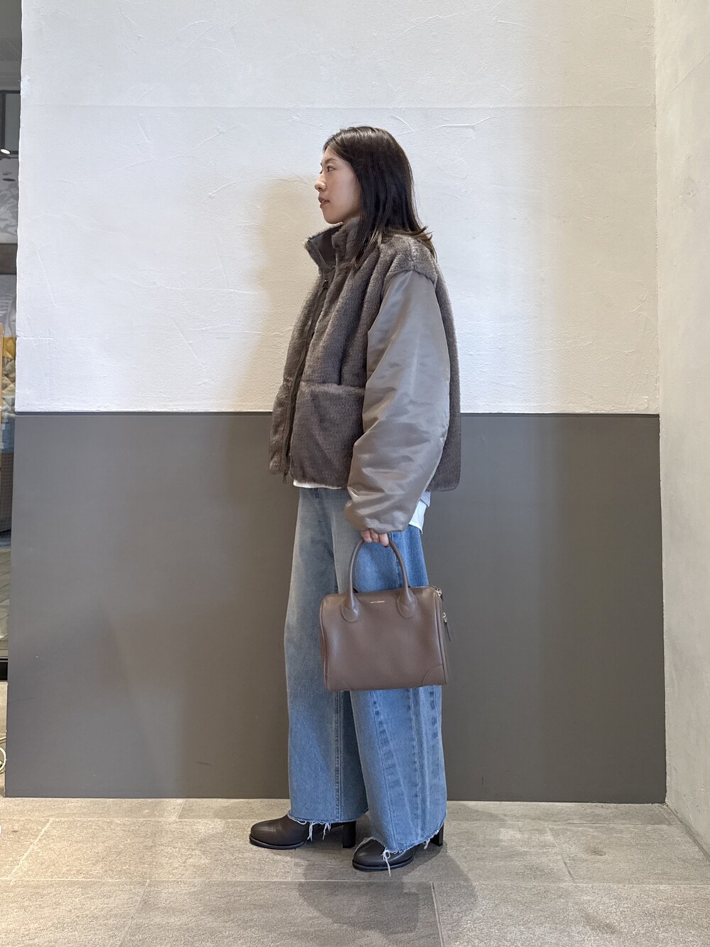 グリーン系のブルゾン、ブルー系のデニムパンツ、グレー系のニット/セーターを着用したレディースの秋コーディネートの4枚目の写真