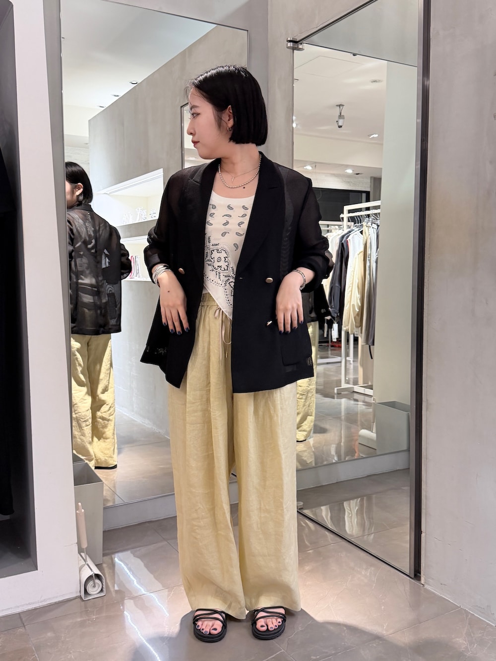 イエロー系のその他パンツ、ブラック系のテーラードジャケット、ホワイト系のストール/ショールを着用したレディースの夏コーディネートの3枚目の写真