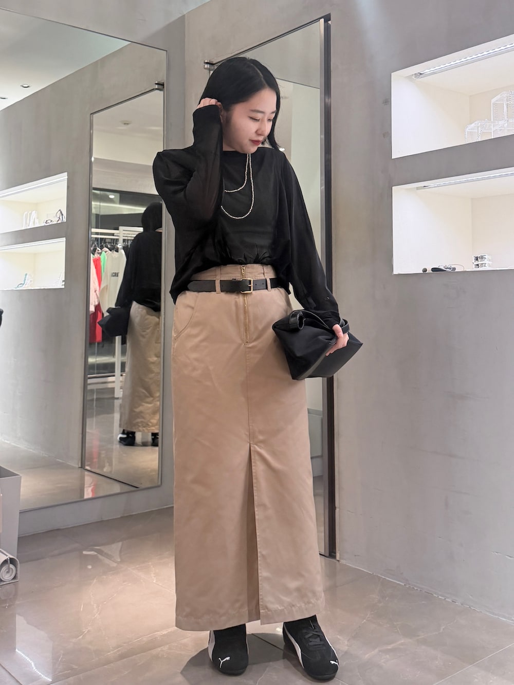 ベージュ系のスカート、ブラック系のショルダーバッグ、ブラック系のTシャツ/カットソーを着用したレディースの夏コーディネートの2枚目の写真