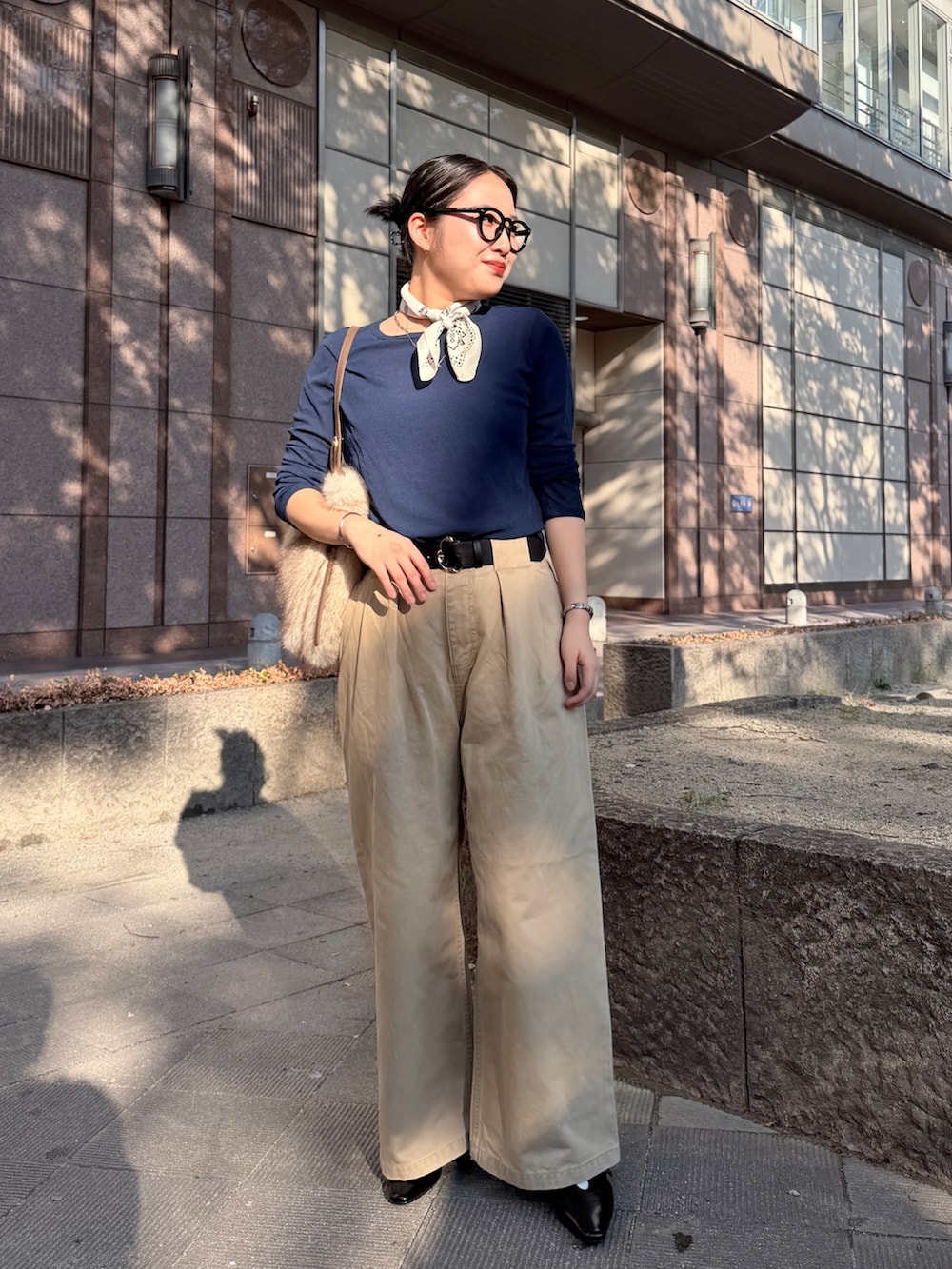 ブラック系のパンプス、ベージュ系のチノパンツ、ホワイト系のトートバッグを着用したレディースの秋コーディネートの3枚目の写真