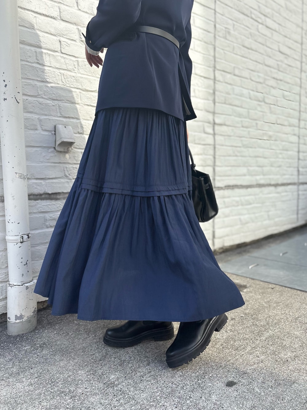 ブルー系のテーラードジャケット、ブルー系のワンピース、ブラック系のブーツを着用したレディースの秋コーディネートの6枚目の写真