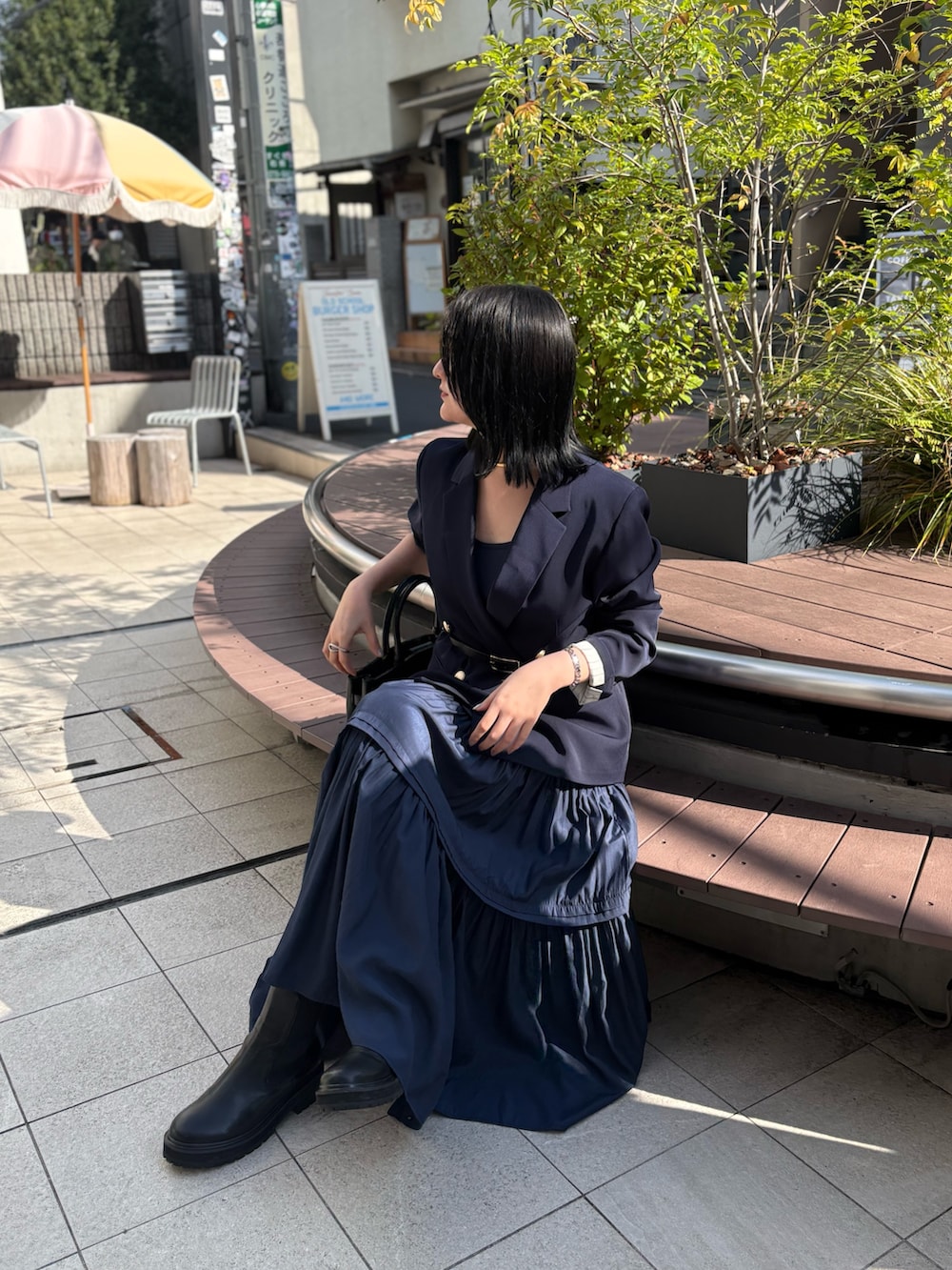 ブルー系のテーラードジャケット、ブルー系のワンピース、ブラック系のブーツを着用したレディースの秋コーディネートの5枚目の写真