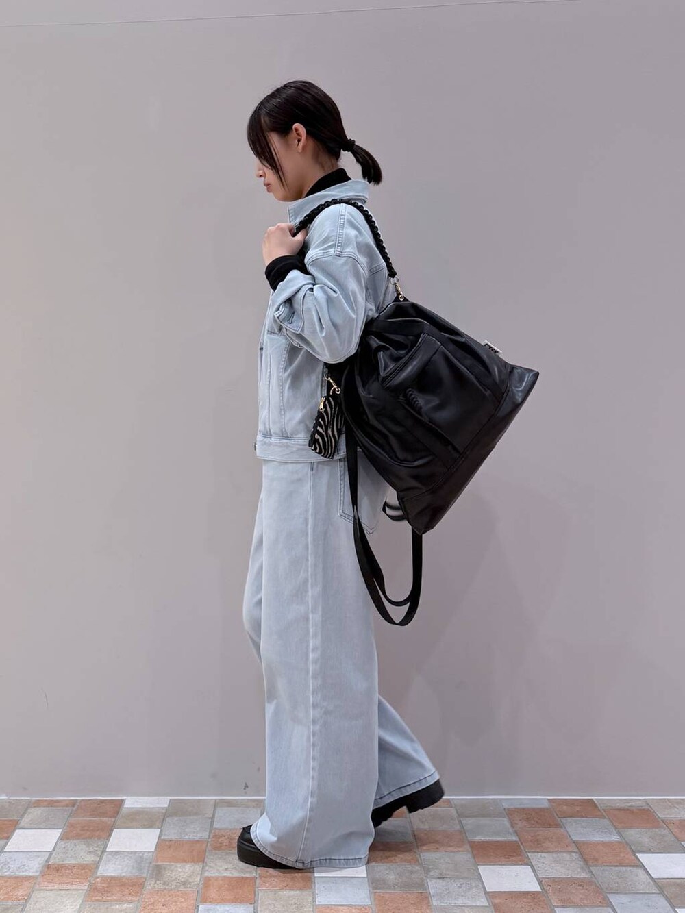 ブラック系のバックパック/リュック、ブルー系のデニムパンツ、ブルー系のデニムジャケットを着用したレディースの冬コーディネートの2枚目の写真