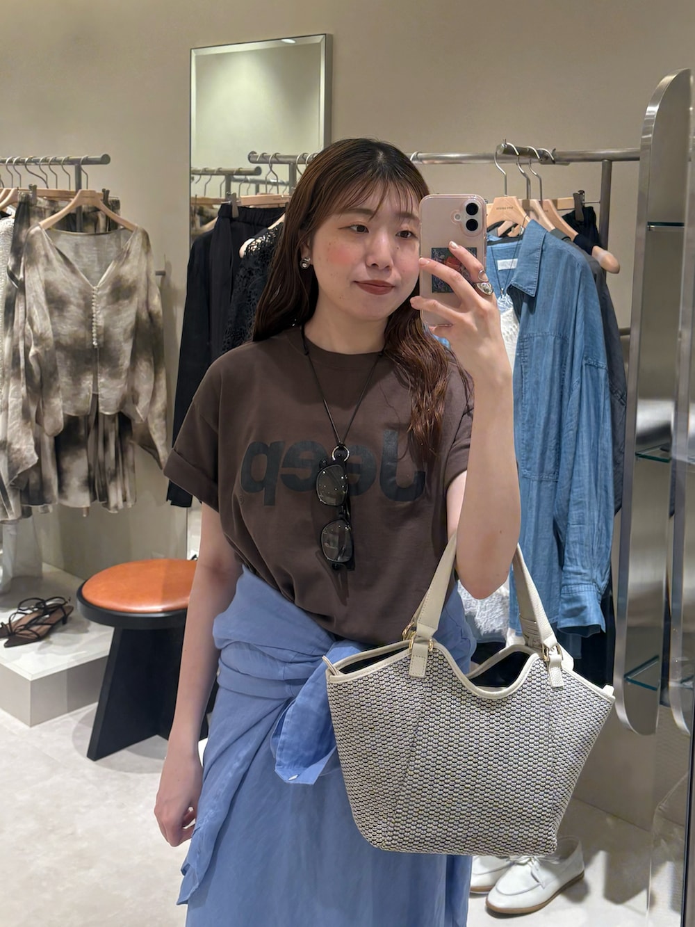 ブラウン系のTシャツ/カットソー、ホワイト系のハンドバッグ、ブルー系のスカートを着用したレディースの夏コーディネートの2枚目の写真