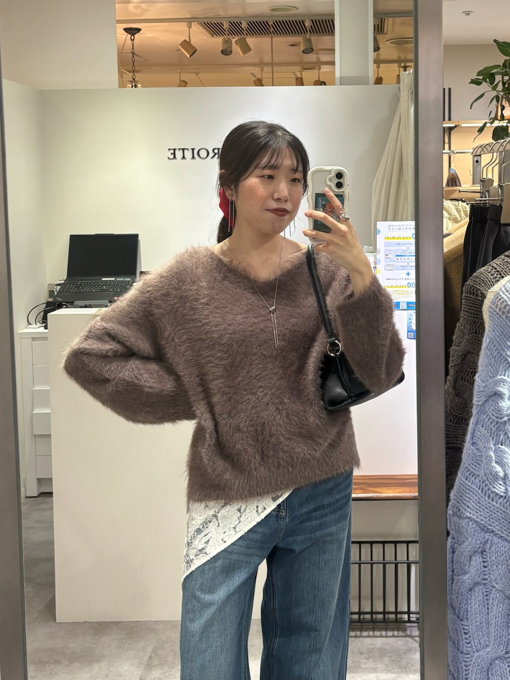 ブラウン系のニット/セーター、ブルー系のデニムパンツ、ブラック系のハンドバッグを着用したレディースの秋コーディネートの2枚目の写真