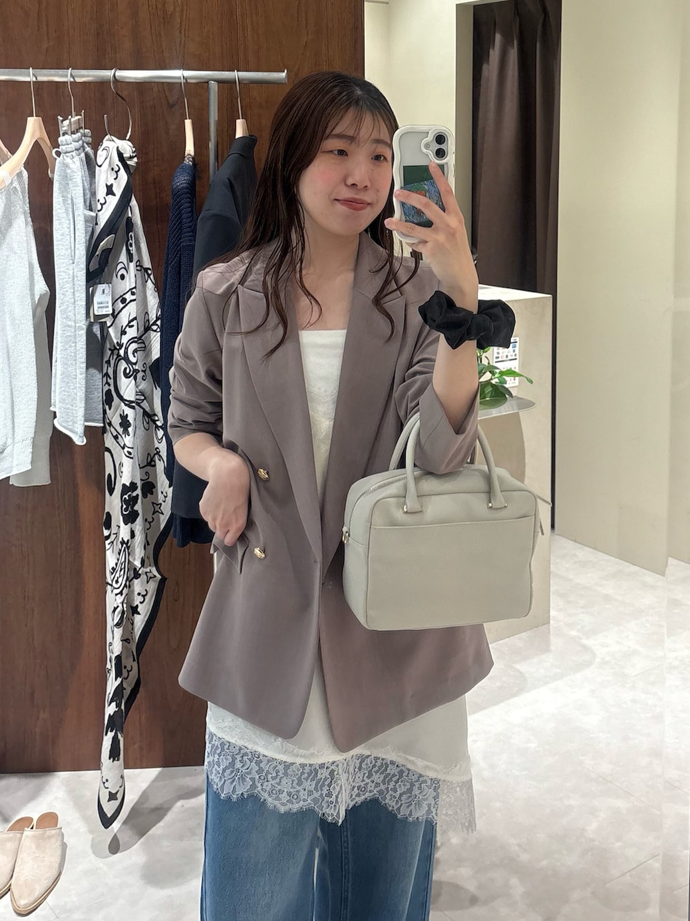 ブラウン系のテーラードジャケット、ホワイト系のキャミソール、ブルー系のデニムパンツを着用したレディースの春コーディネートの2枚目の写真