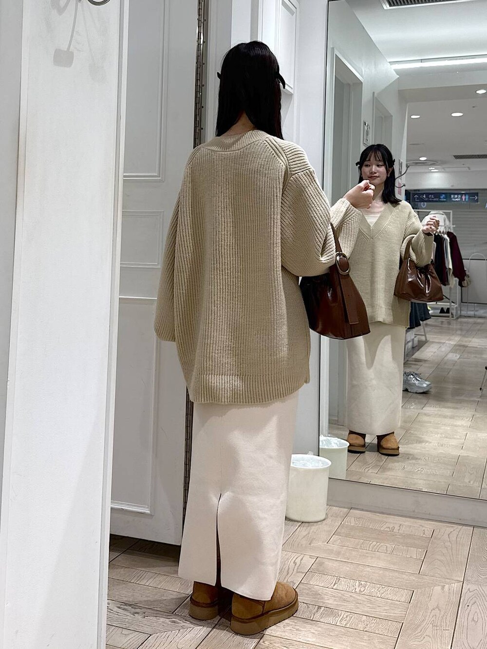 ホワイト系のスカート、ベージュ系のブーツ、ブラウン系のショルダーバッグを着用したレディースの冬コーディネートの3枚目の写真