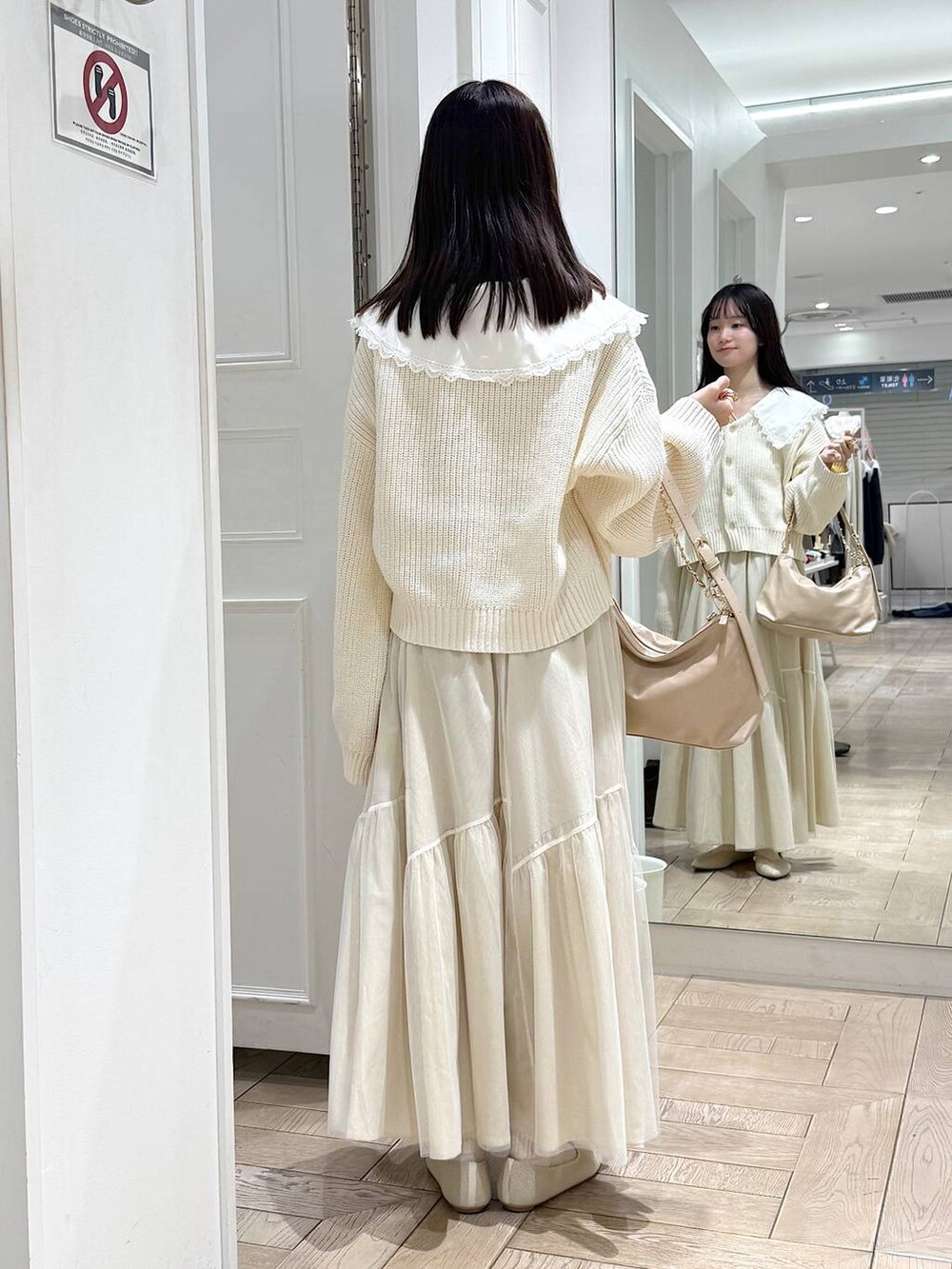 ベージュ系のショルダーバッグ、ホワイト系のパンプス、ホワイト系のスカートを着用したレディースの冬コーディネートの3枚目の写真