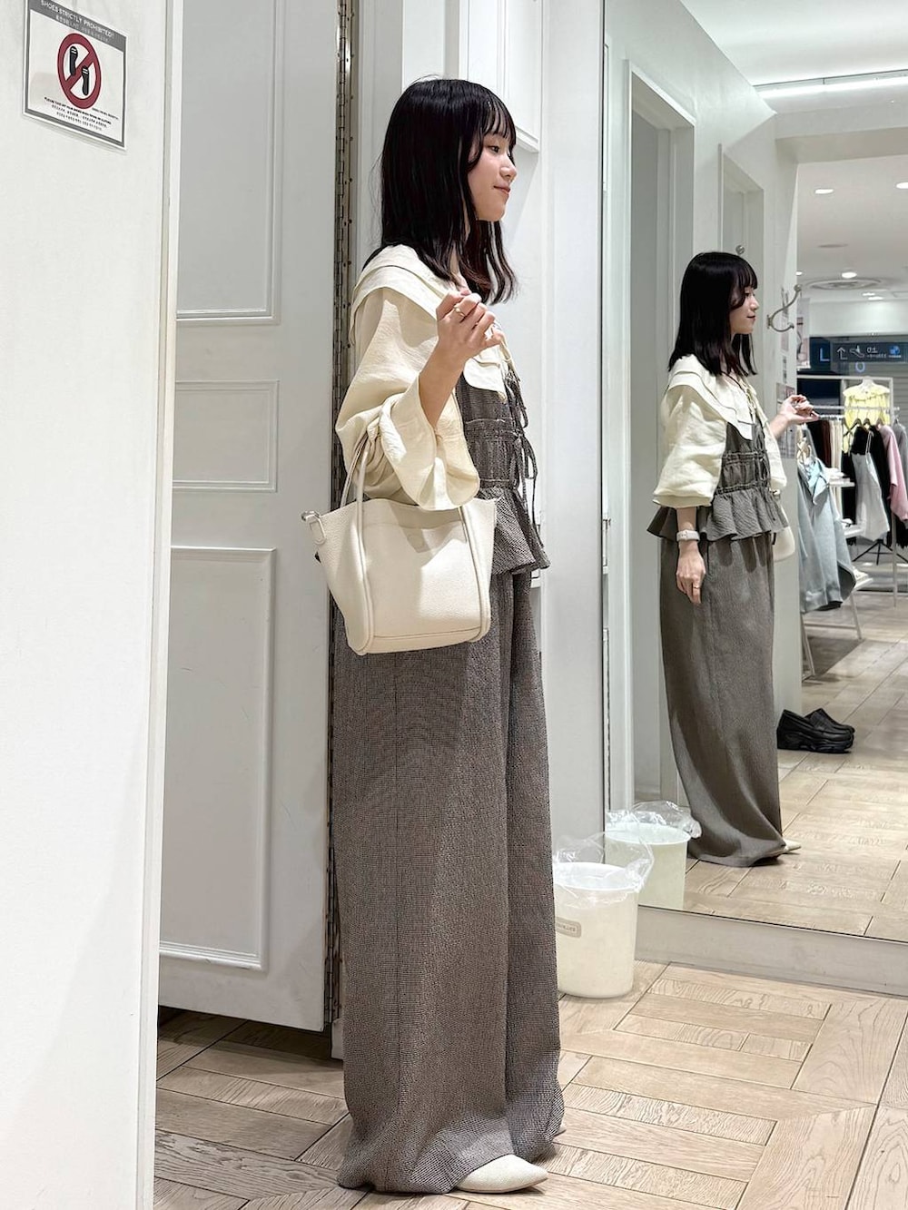 ホワイト系のショルダーバッグ、ホワイト系のパンプス、ホワイト系のシャツ/ブラウスを着用したレディースの春コーディネートの2枚目の写真