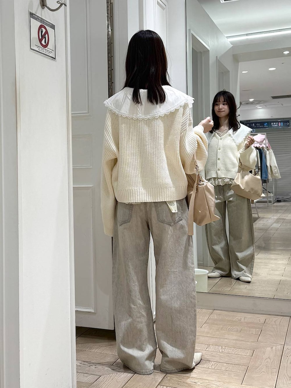 ベージュ系のデニムパンツ、ベージュ系のショルダーバッグ、ホワイト系のパンプスを着用したレディースの冬コーディネートの3枚目の写真