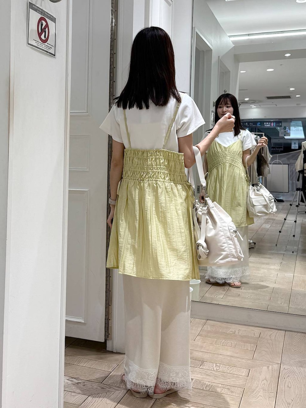 イエロー系のワンピース、ホワイト系のTシャツ/カットソー、ホワイト系のサンダルを着用したレディースの夏コーディネートの3枚目の写真