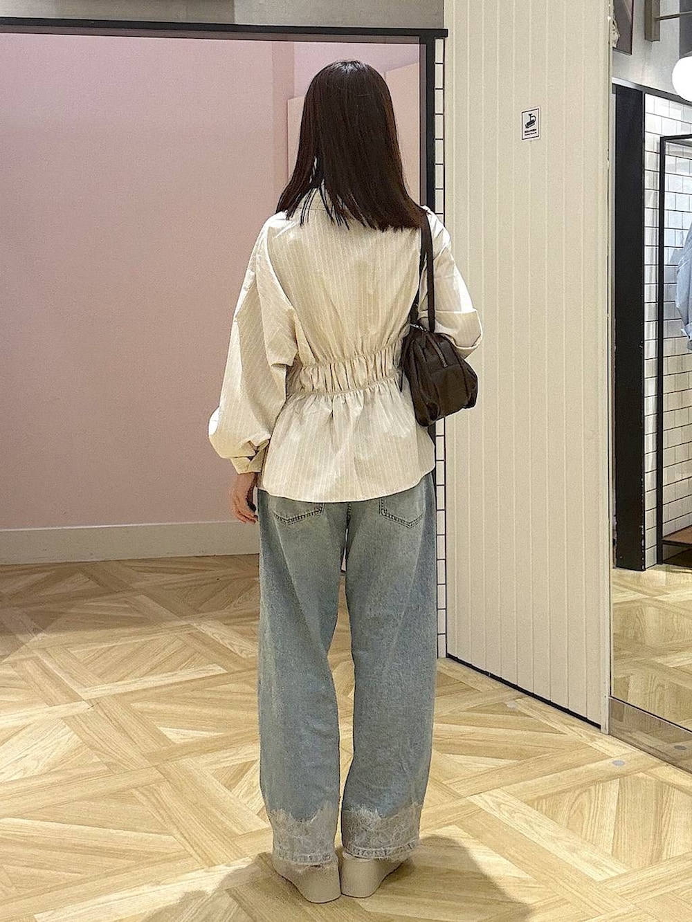 ブラウン系のボストンバッグ、ブルー系のデニムパンツ、ホワイト系のサンダルを着用したレディースの夏コーディネートの3枚目の写真