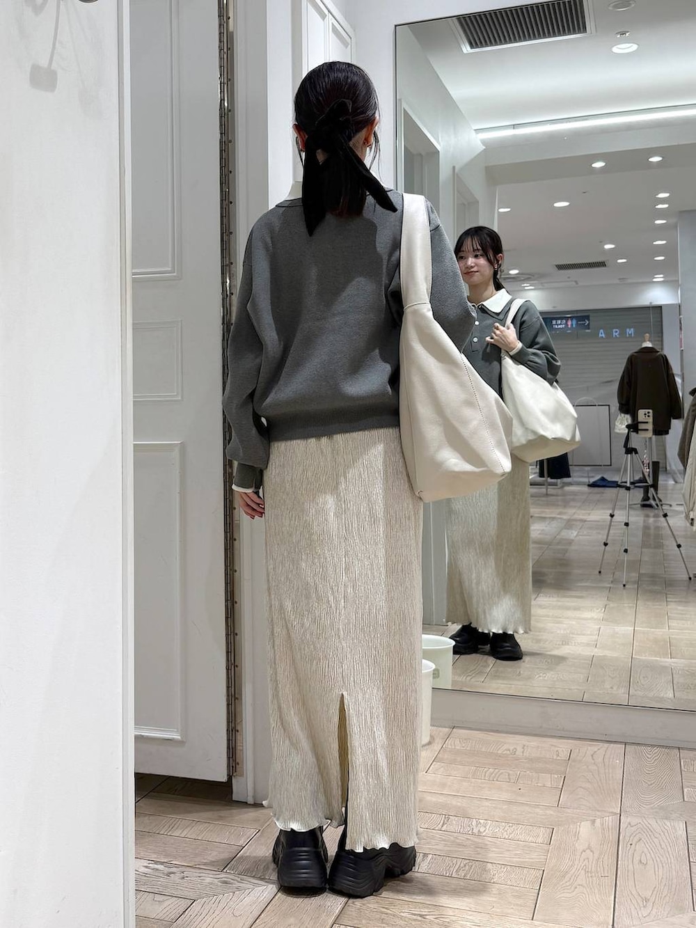 ブラック系のブーツ、ホワイト系のスカート、グレー系のニット/セーターを着用したレディースの冬コーディネートの3枚目の写真