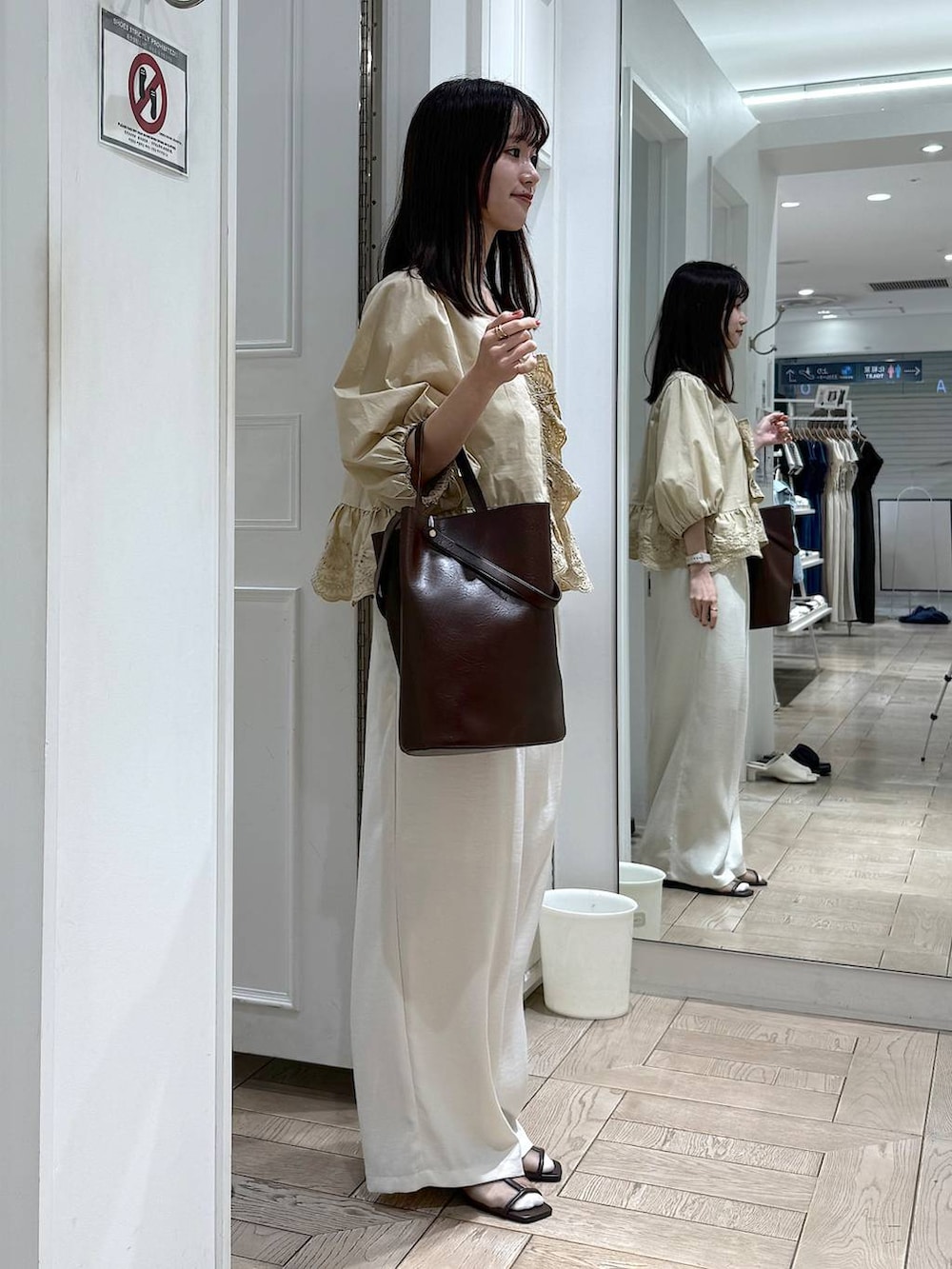 ベージュ系のシャツ/ブラウス、ホワイト系のその他パンツ、ブラウン系のトートバッグを着用したレディースの春コーディネートの2枚目の写真