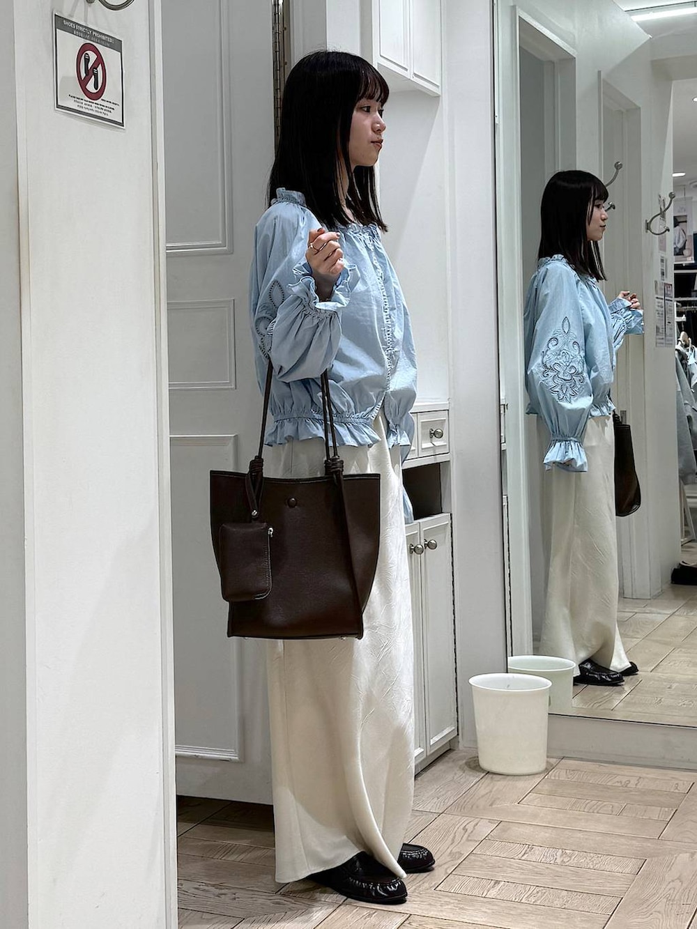 ホワイト系のスカート、ブラウン系のローファー、ブラウン系のトートバッグを着用したレディースの春コーディネートの2枚目の写真