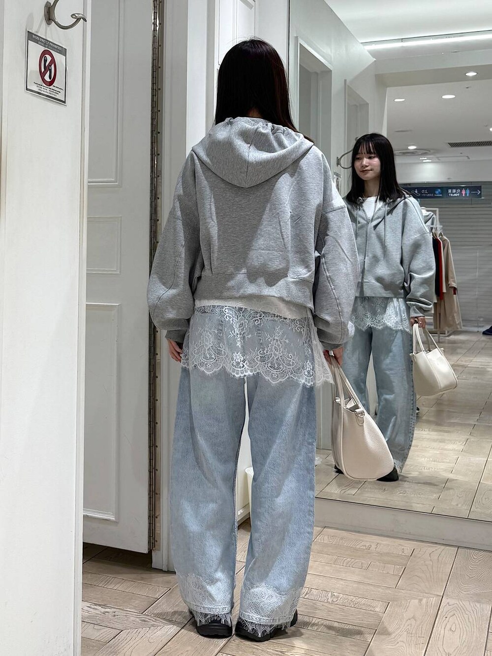 ホワイト系のショルダーバッグ、グレー系のパーカー、ブルー系のデニムパンツを着用したレディースの春コーディネートの3枚目の写真