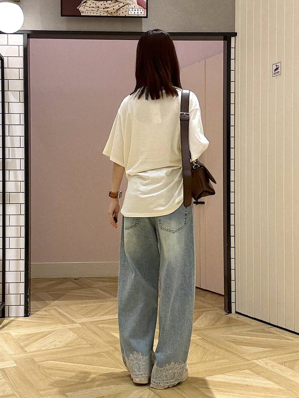 ブラウン系のショルダーバッグ、ベージュ系のTシャツ/カットソー、ブルー系のデニムパンツを着用したレディースの夏コーディネートの3枚目の写真