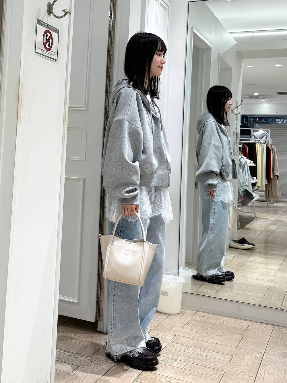 ホワイト系のショルダーバッグ、グレー系のパーカー、ブルー系のデニムパンツを着用したレディースの春コーディネートの2枚目の写真
