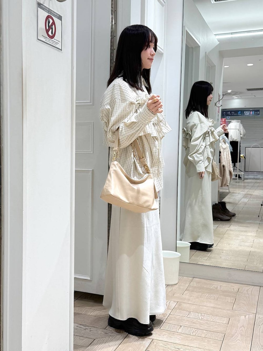 ホワイト系のスカート、ベージュ系のショルダーバッグ、ブラウン系のローファーを着用したレディースの冬コーディネートの2枚目の写真