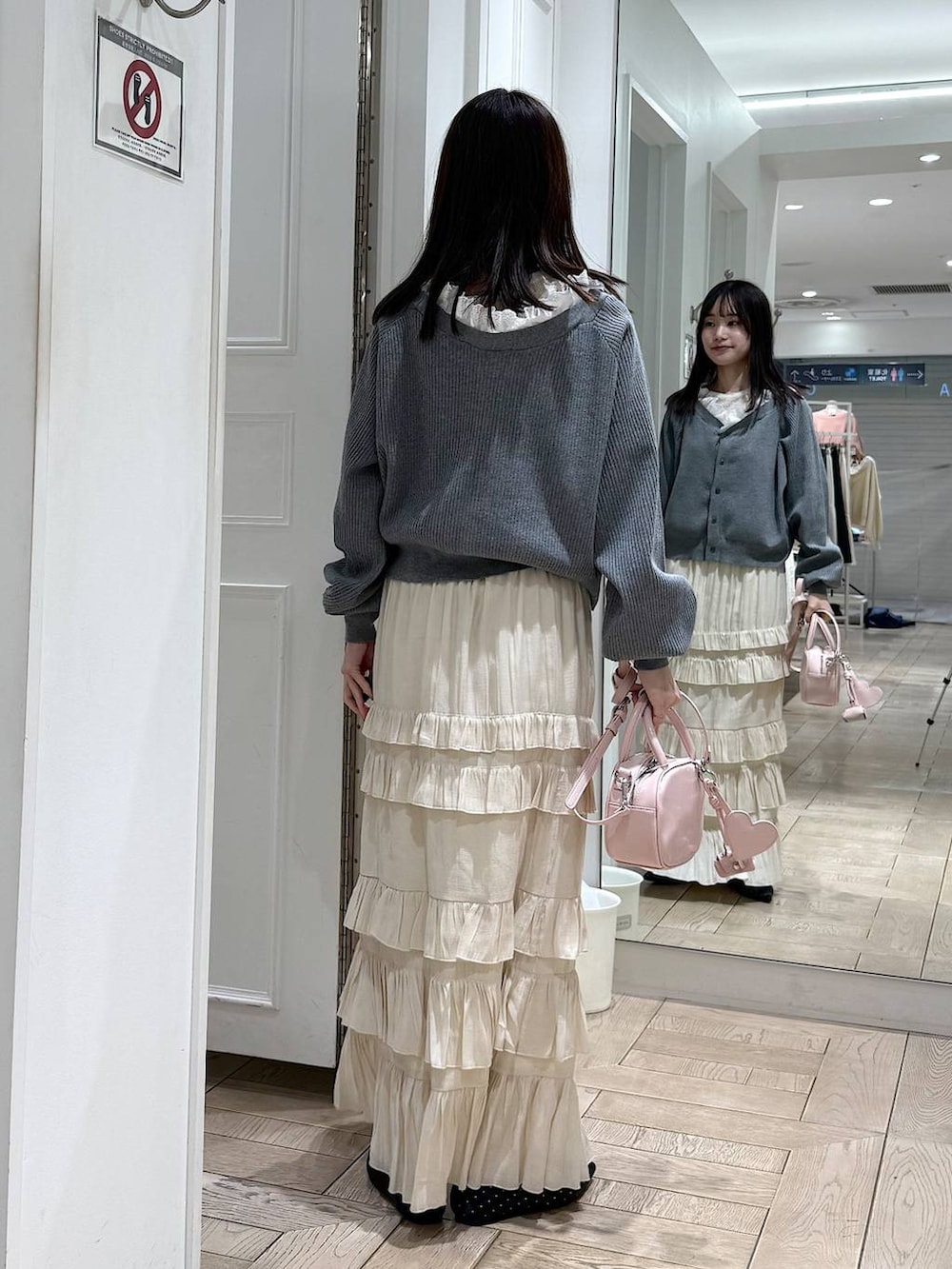 ブラック系のパンプス、ピンク系のボストンバッグ、ホワイト系のスカートを着用したレディースの冬コーディネートの3枚目の写真