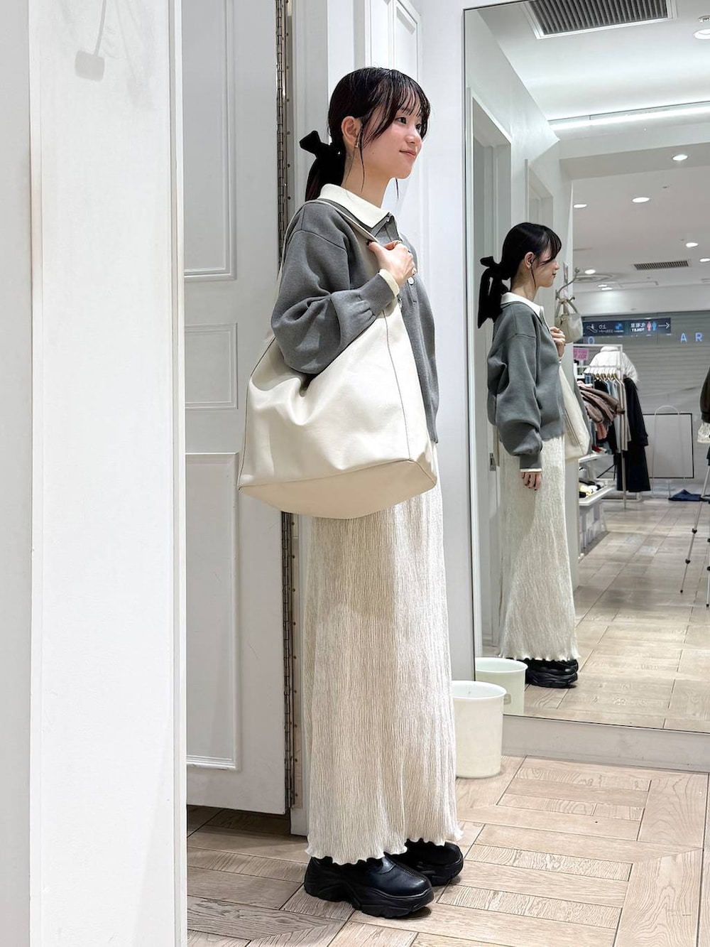 ブラック系のブーツ、ホワイト系のスカート、グレー系のニット/セーターを着用したレディースの冬コーディネートの2枚目の写真