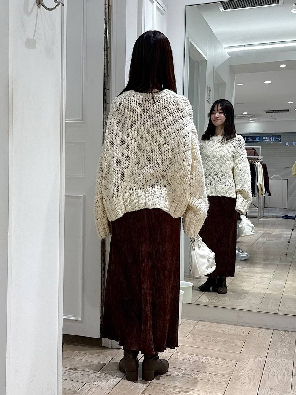 ブラウン系のスカート、ホワイト系のニット/セーター、ブラウン系のブーツを着用したレディースの冬コーディネートの3枚目の写真
