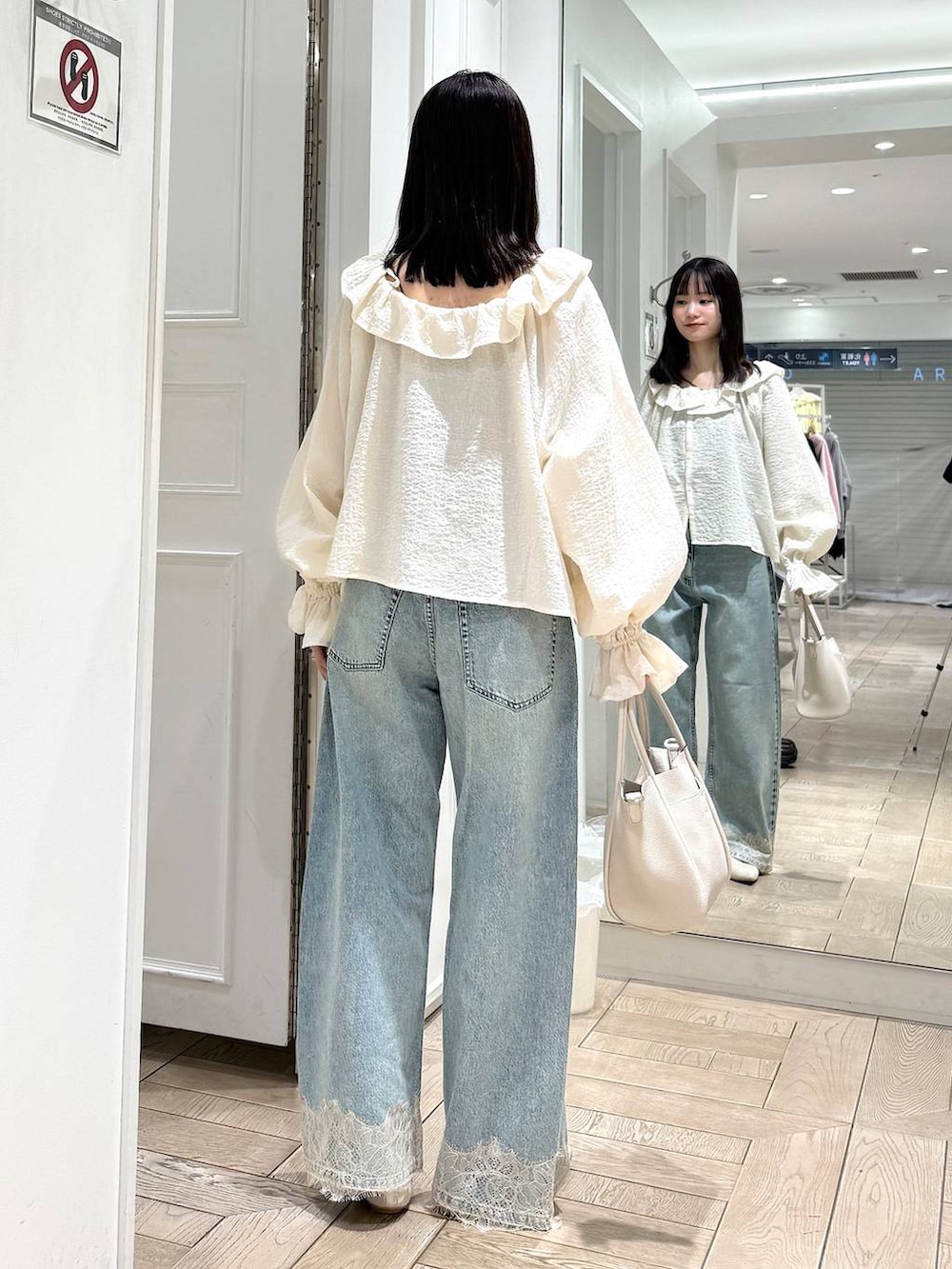 ホワイト系のショルダーバッグ、ブルー系のデニムパンツ、ホワイト系のパンプスを着用したレディースの春コーディネートの3枚目の写真