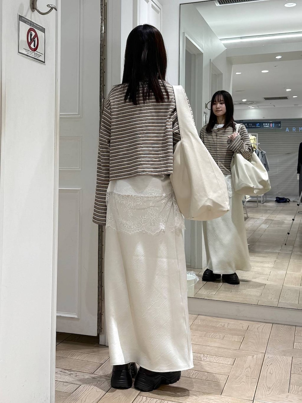 ホワイト系のスカート、ホワイト系のショルダーバッグ、ブラウン系のローファーを着用したレディースの春コーディネートの3枚目の写真