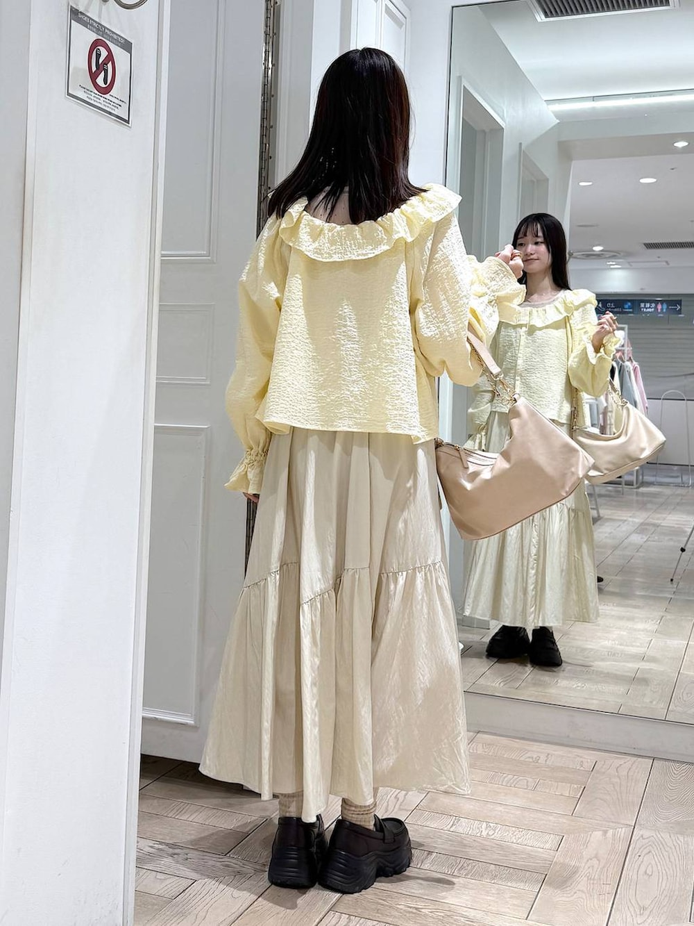 ベージュ系のショルダーバッグ、ブラウン系のローファー、イエロー系のシャツ/ブラウスを着用したレディースの冬コーディネートの3枚目の写真