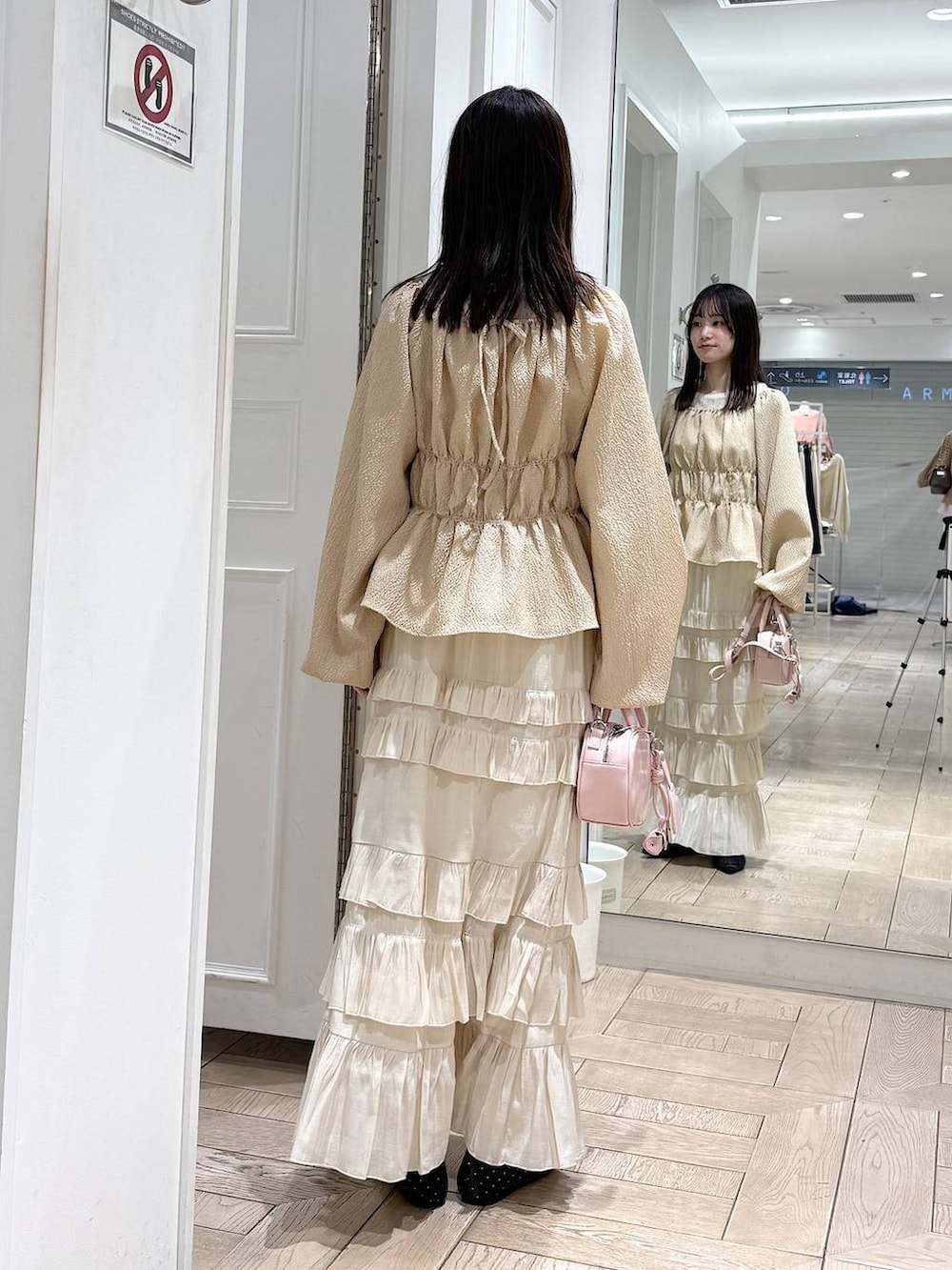 ブラック系のパンプス、ピンク系のボストンバッグ、ホワイト系のスカートを着用したレディースの冬コーディネートの3枚目の写真