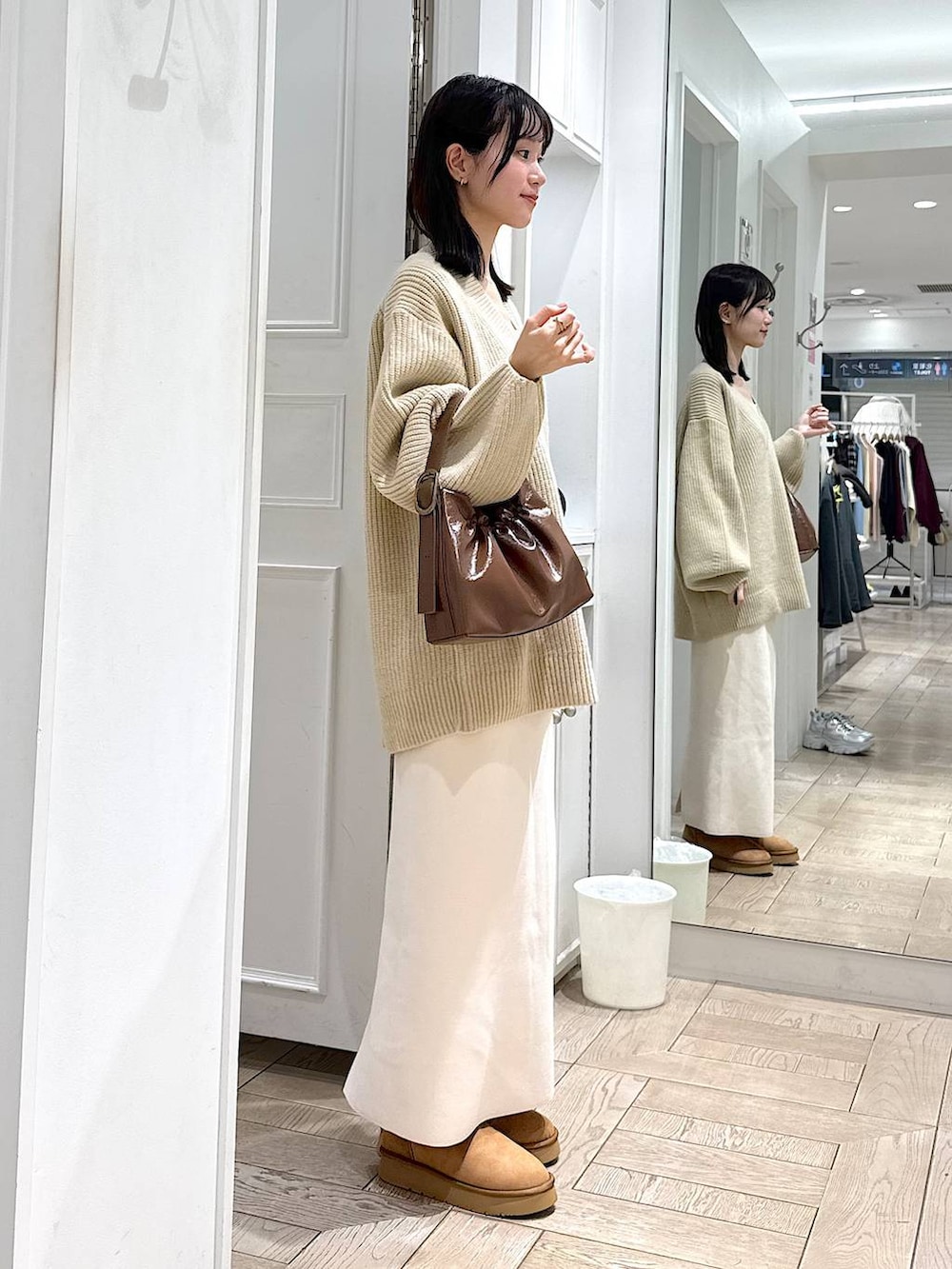 ホワイト系のスカート、ベージュ系のブーツ、ブラウン系のショルダーバッグを着用したレディースの冬コーディネートの2枚目の写真