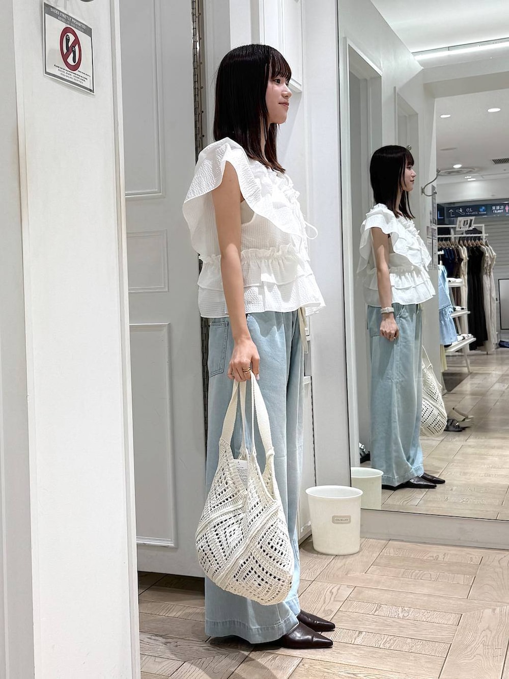 ブラウン系のサンダル、ブルー系のデニムパンツ、ホワイト系のトートバッグを着用したレディースの夏コーディネートの2枚目の写真