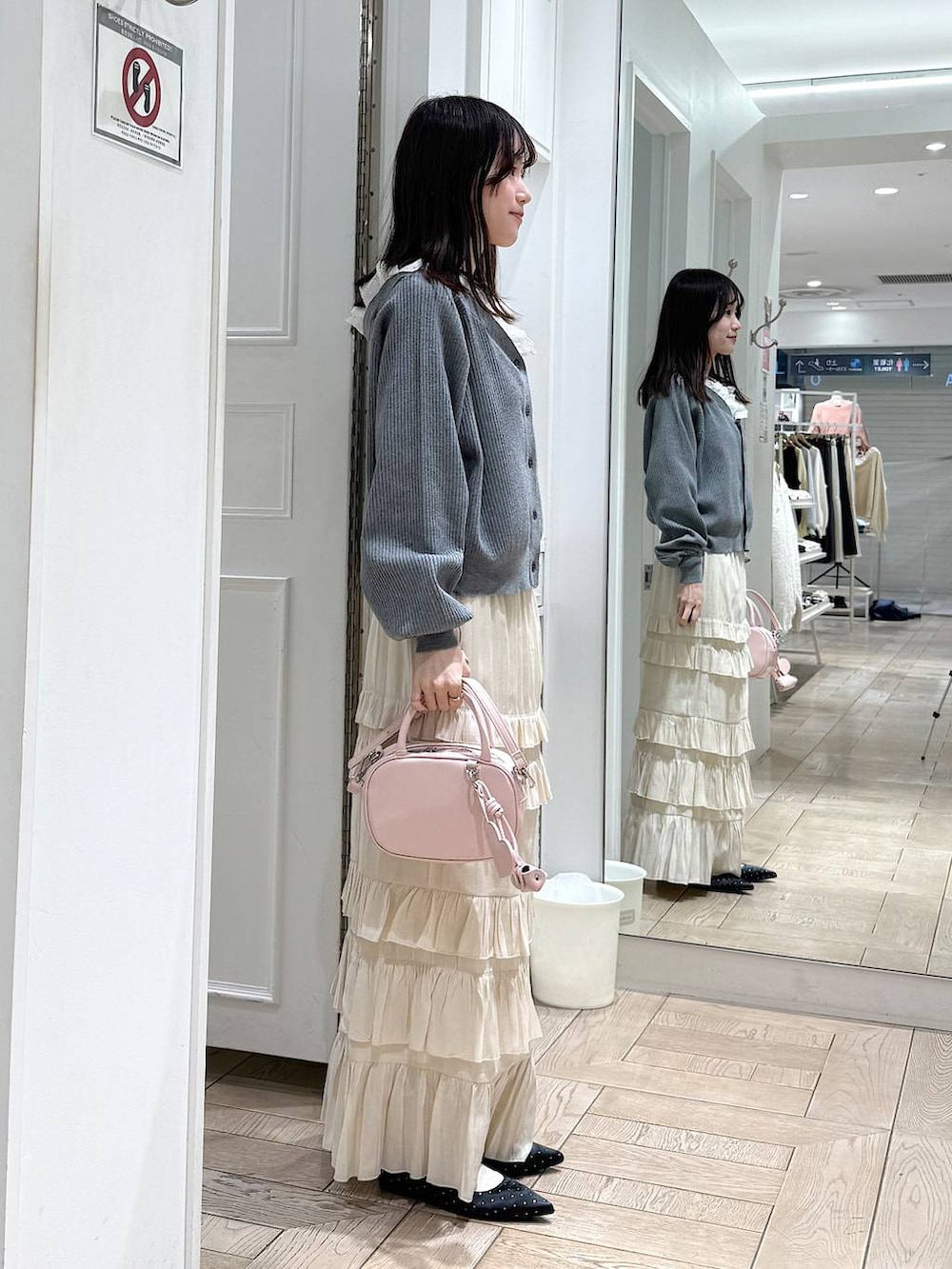 ブラック系のパンプス、ピンク系のボストンバッグ、ホワイト系のスカートを着用したレディースの冬コーディネートの2枚目の写真